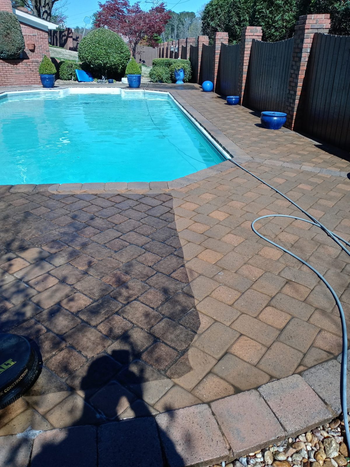 Freshly cleaned brick paver pool deck beside a bright blue swimming pool